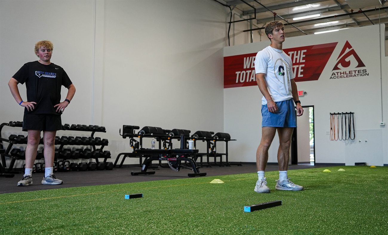 An athlete set on the turf while a coach watches